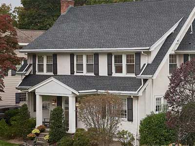 Front view of a white mid-class home with gray GAF shingles on its roof