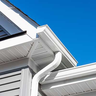 Close up of white, k-style gutters with a downspout