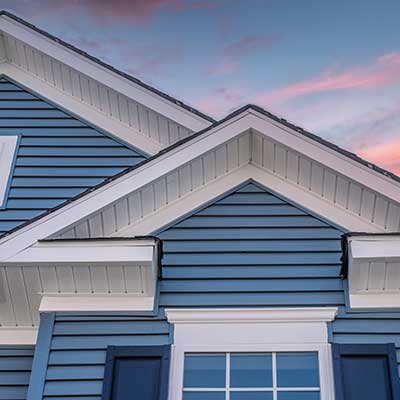 Close up of a home with blue siding as the sun sets above