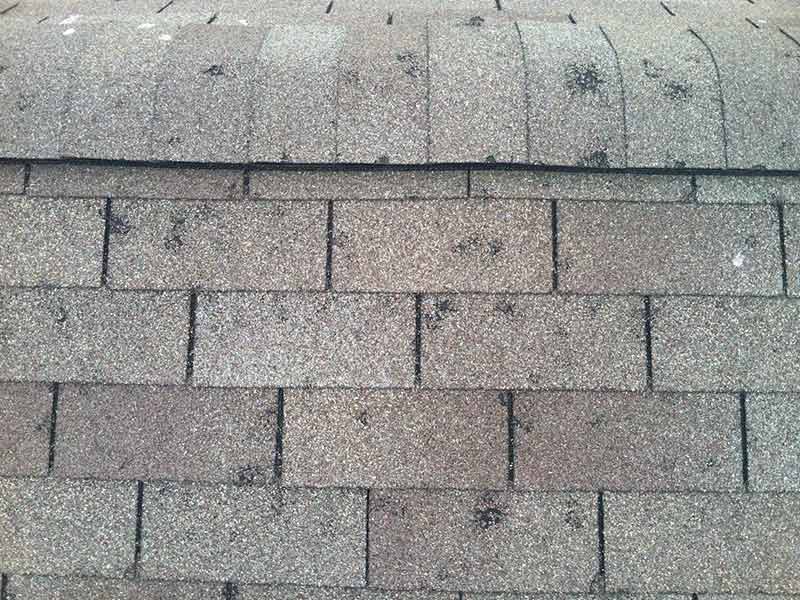 Close up of a residential shingle roof with visible spots of hail damage