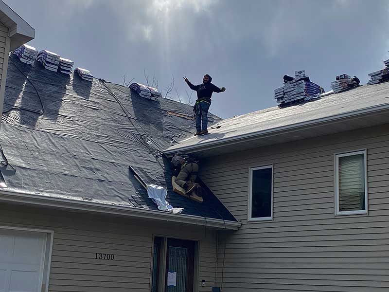 Two Clear Point Construction, Inc. workers in the middle of a residential roof replacement, but one worker is posing for the picture
